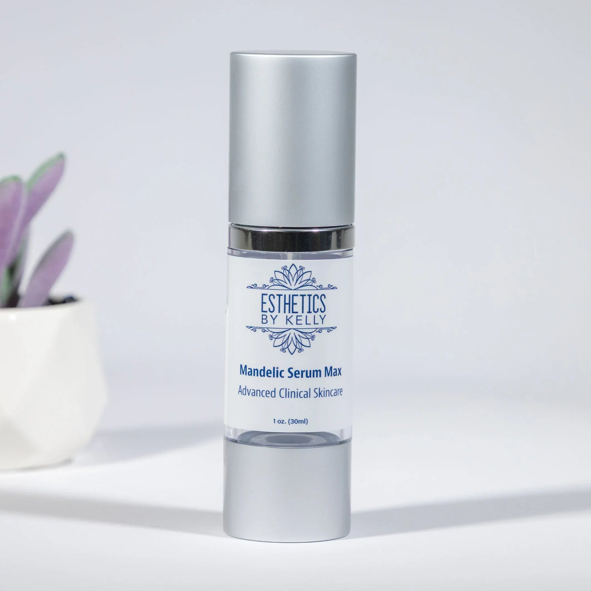 Mandelic Serum Max skincare bottle with silver cap on a light background, plant nearby